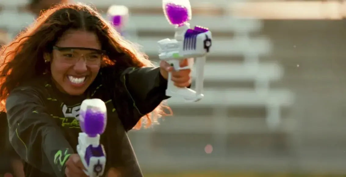 Gel Blaster Girl Firing Two Purple Blasters